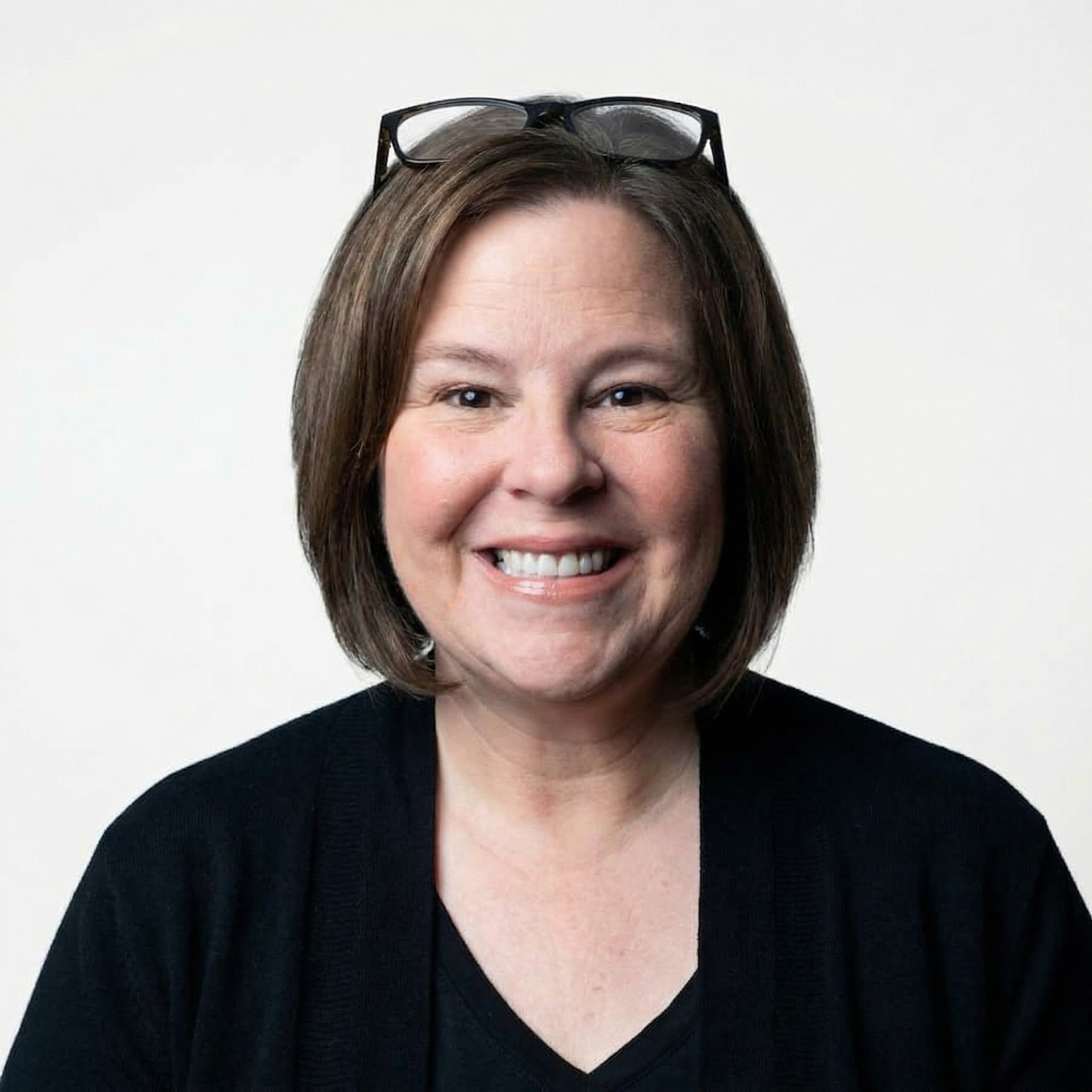 Carrie, creator and author of Letters from The Ledford House, smiling in a black cardigan with glasses pushed up on her head